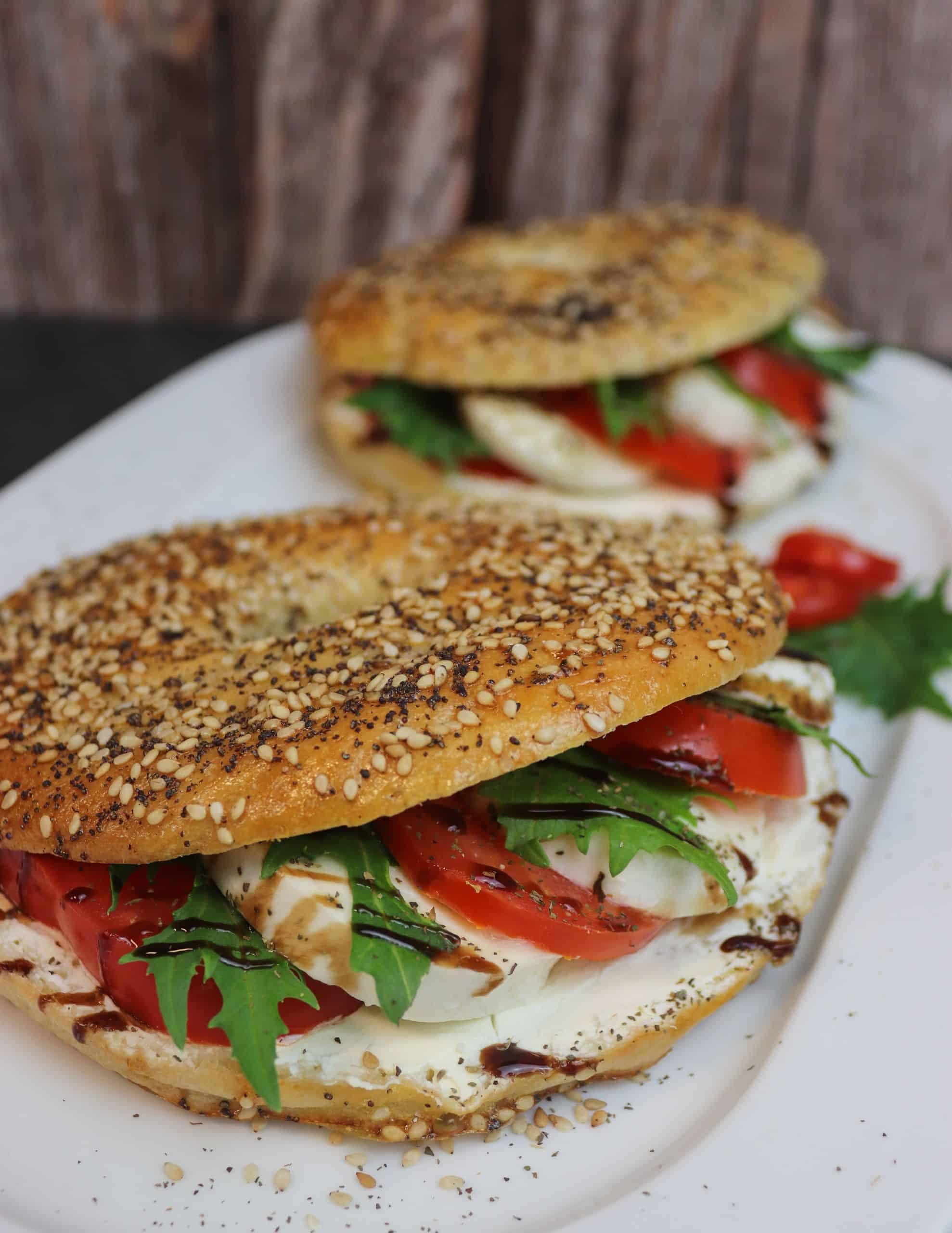 Zwei leckere Tomaten-Mozzarella-Bagel auf einem Teller.