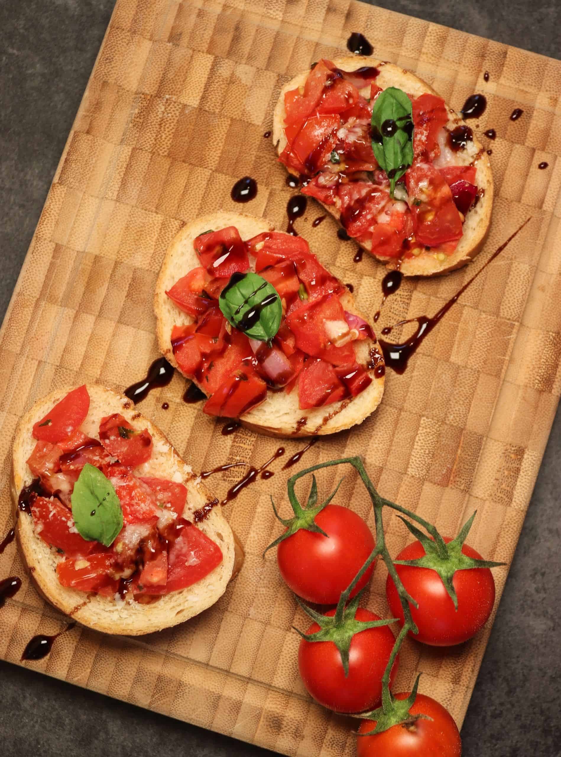 Leckere Bruschetta mit Knoblauch mit ein paar frischen Tomaten auf einem Holzbrett.