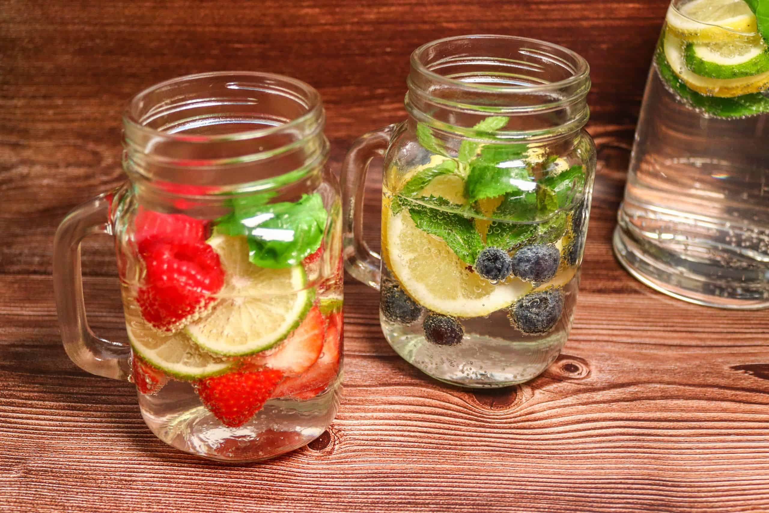 Detox-Water mit Beeren, Zitrone und Minze in zwei Gläsern