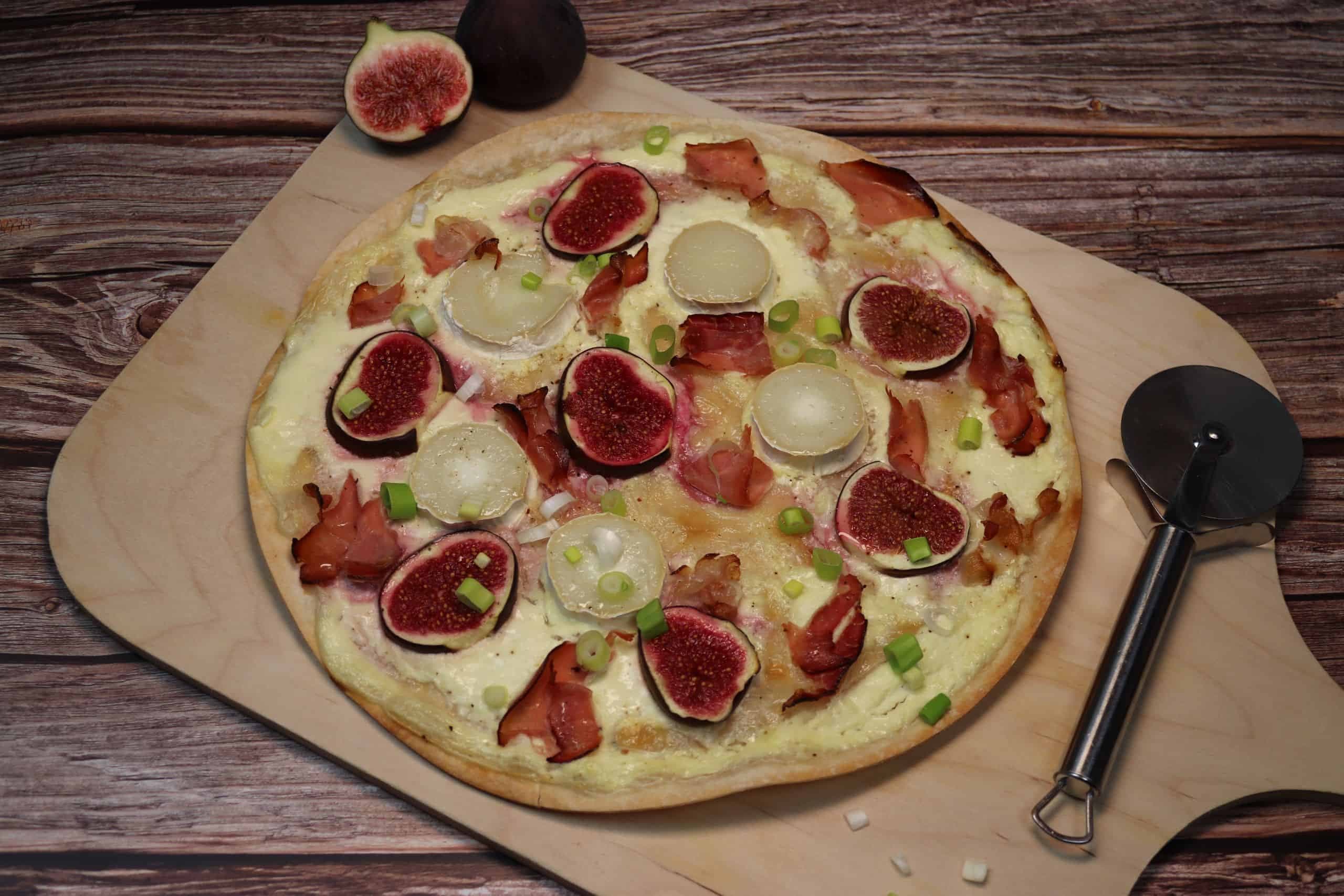 Ein leckerer Ziegenkäse-Feigen-Flammkuchen auf einem Flammkuchenbrett.