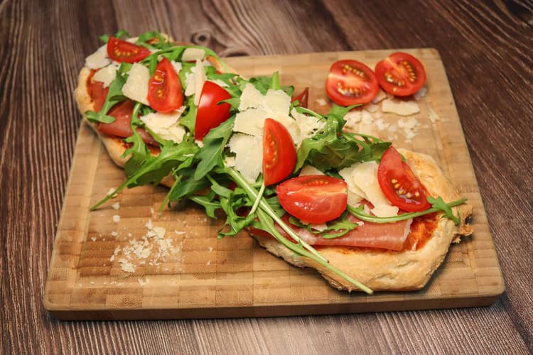 Flat-Bread-Parma mir Rucola, Tomaten und Parmesan auf einem Brett