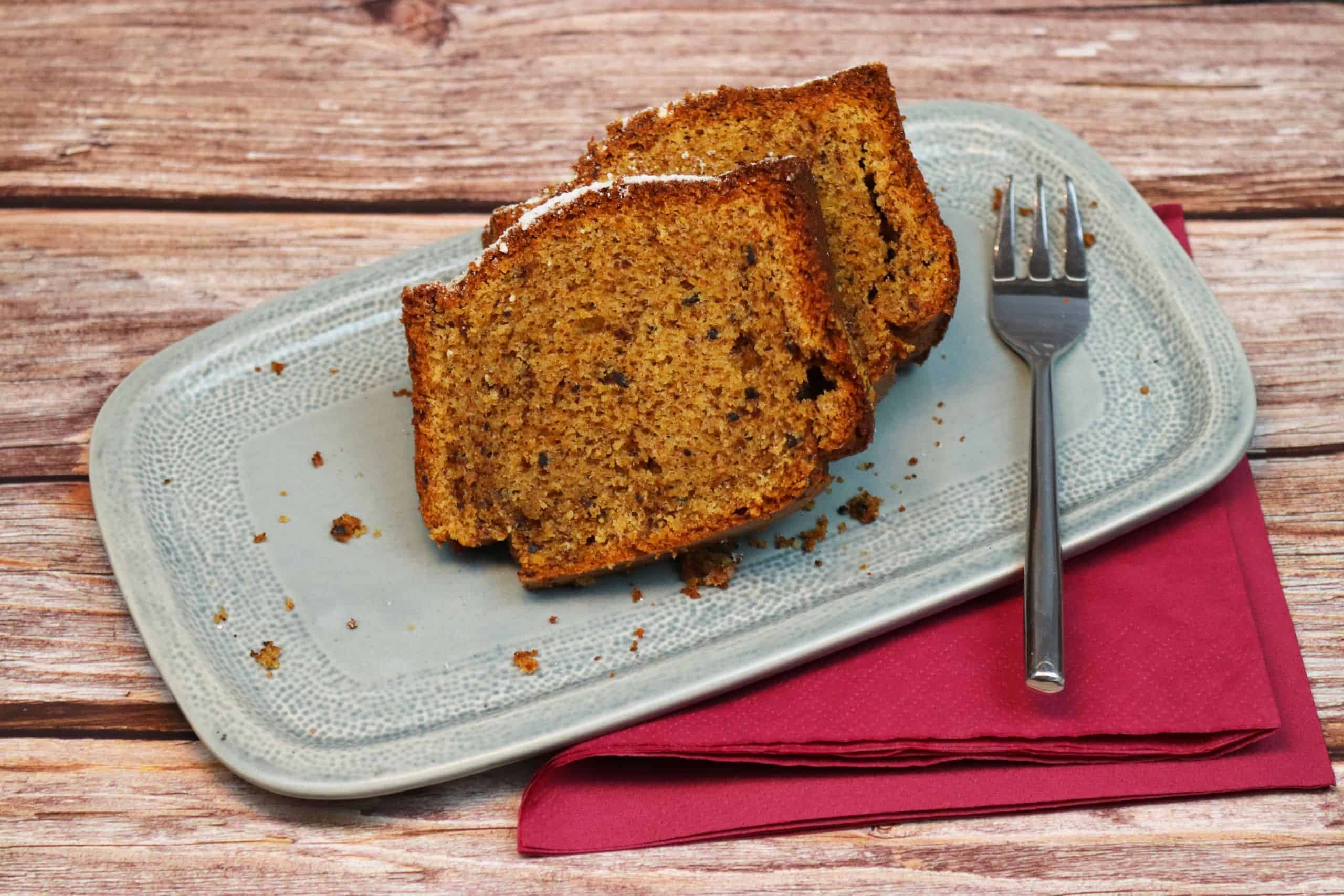 Zwei Stücke leckerer Apfel-Karotten-Schoko-Kuchen mit einer Gabel auf einem Teller.