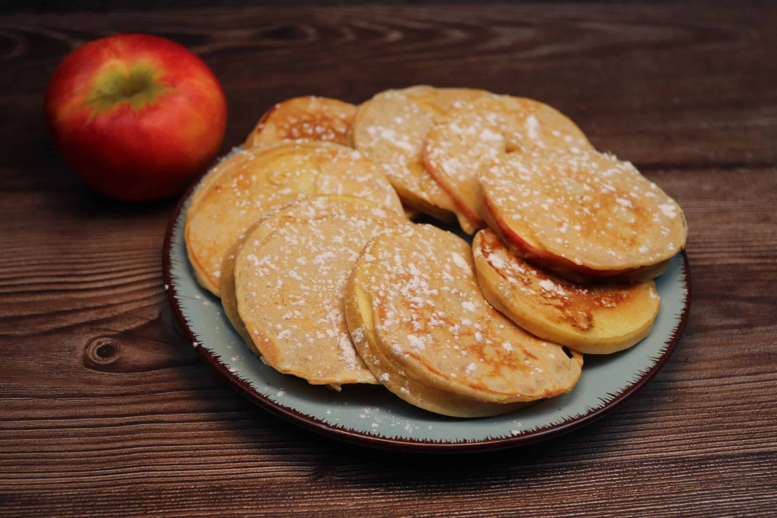 Apfel-Pancakes auf einem Teller mit einem Apfel als Deko