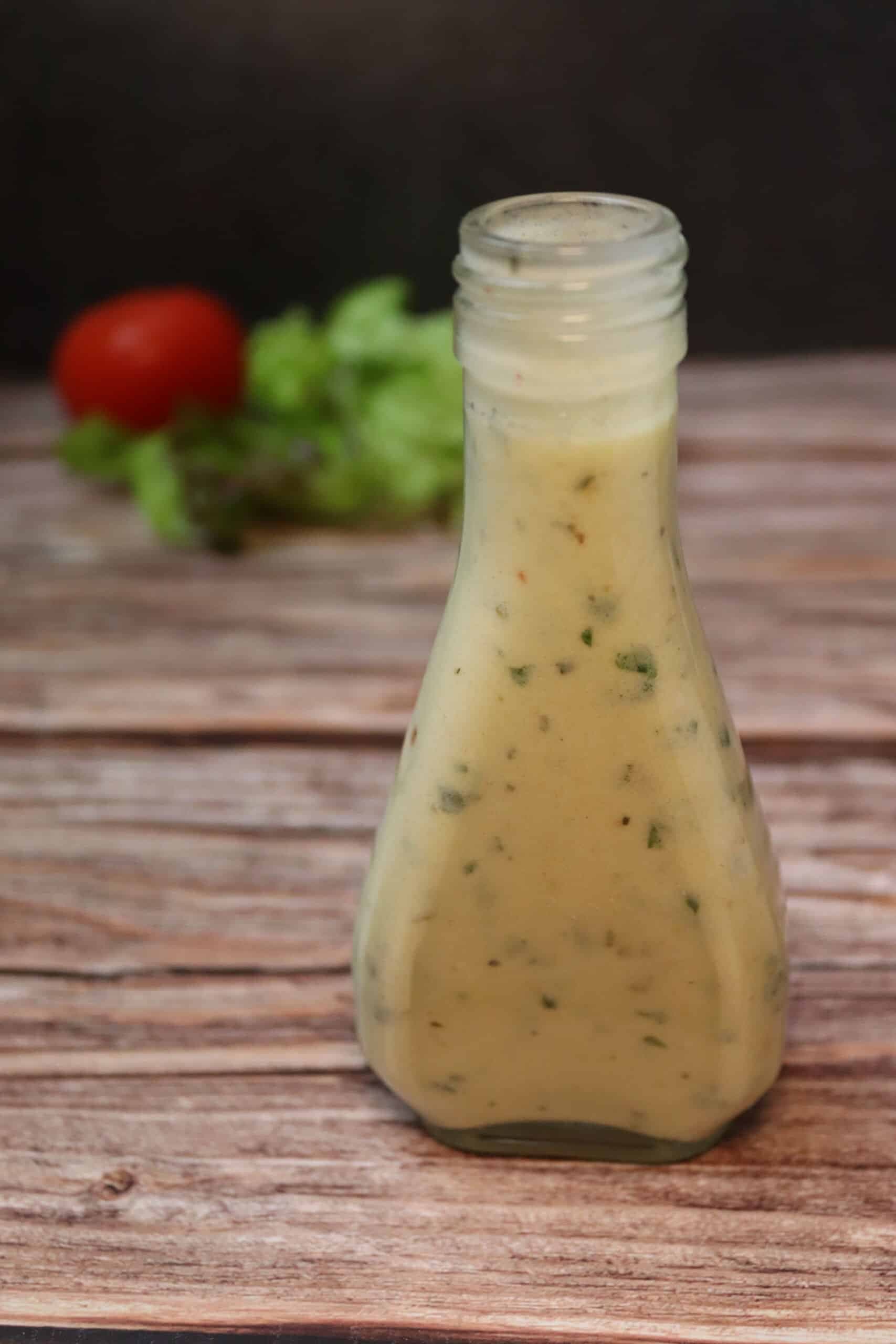 Leckeres Jogurt-Dressing in einer Flasche mit Salat und Tomaten