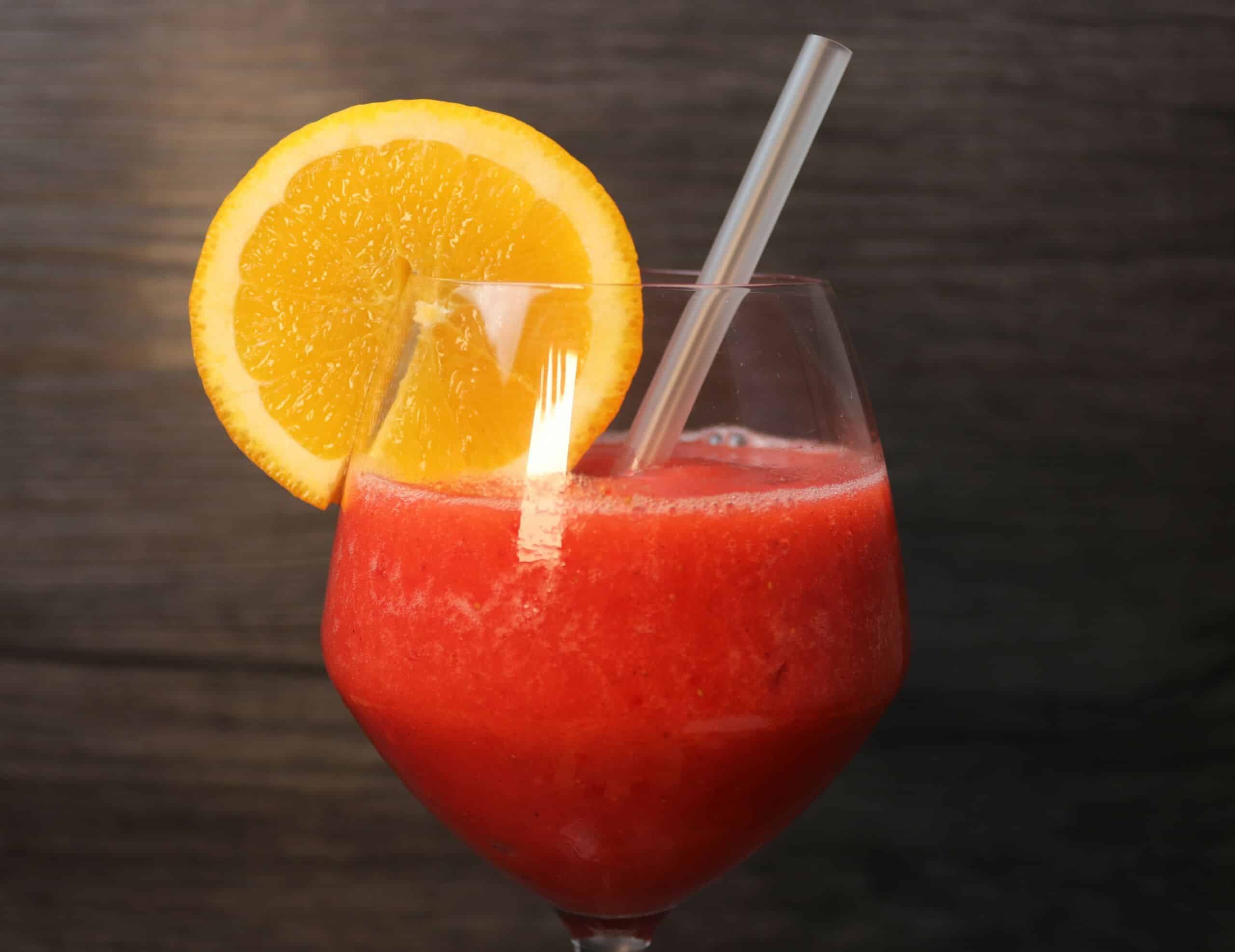 Ein leckerer Strawberry-Daiquiri im Glas mit Orange und Strohhalm