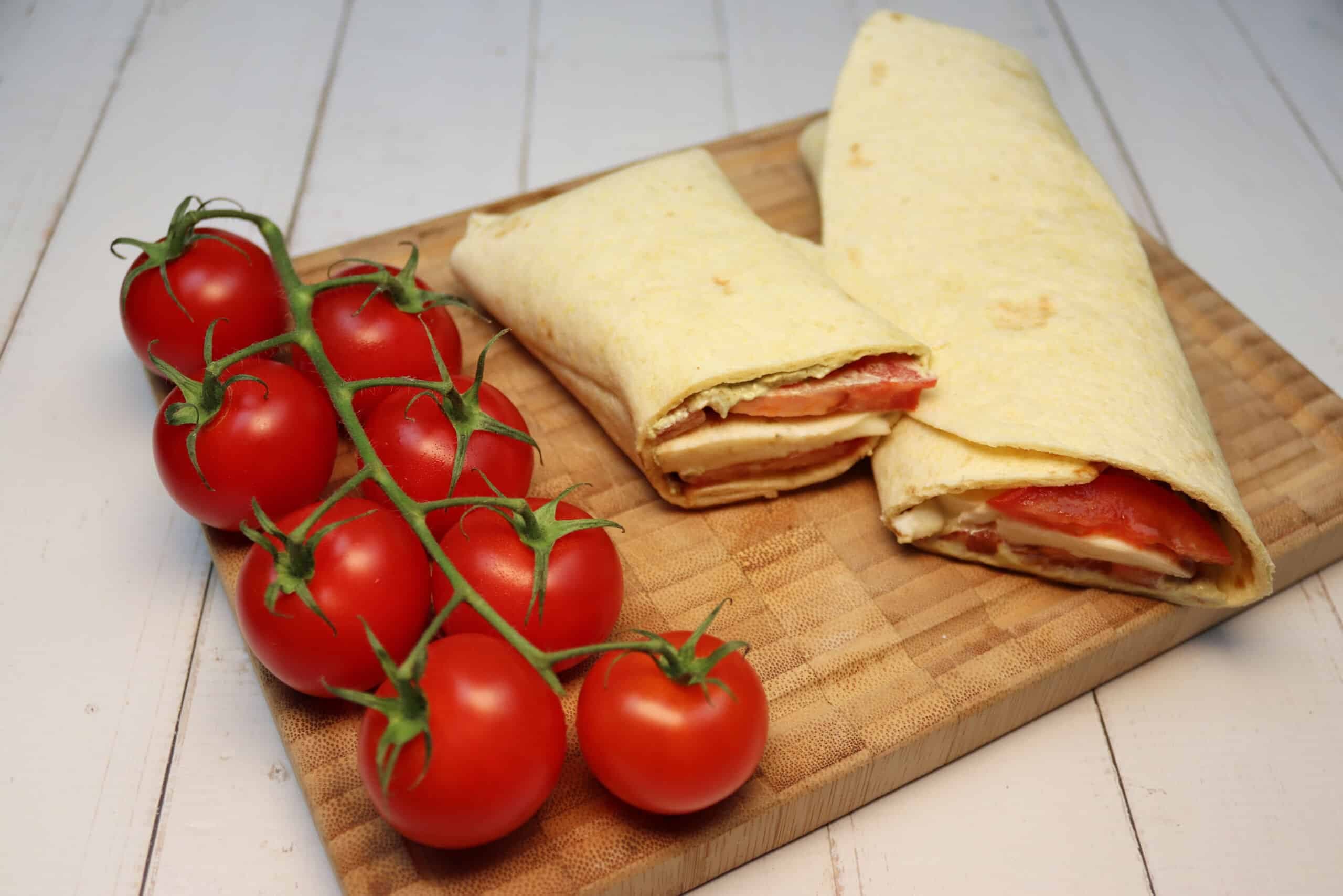 Caprese-Wrap mit Tomaten, Mozzarella, und Pesto auf einem Brett