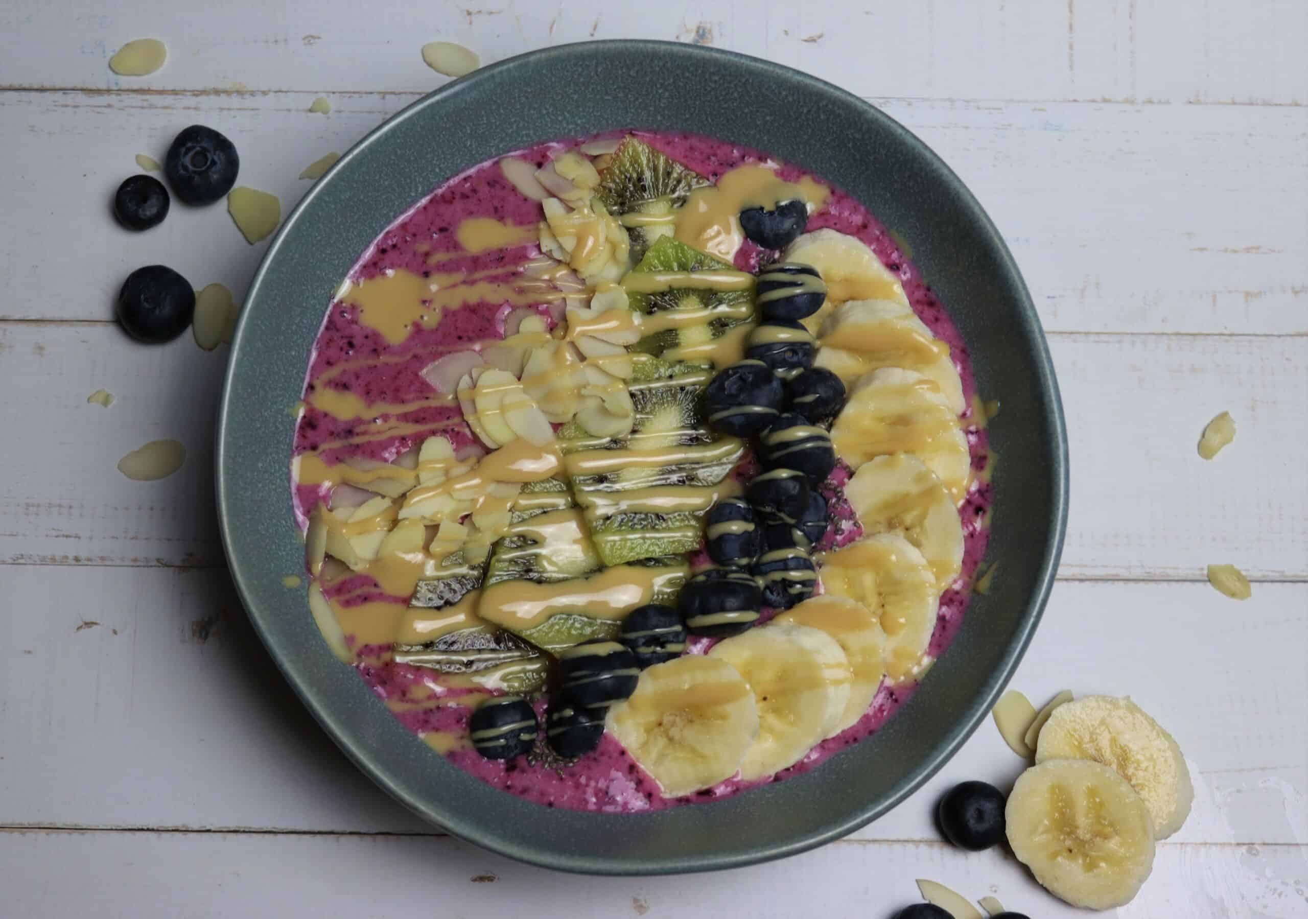 Erdbeer-Smoothie-Bowl mit Heidelbeeren, Bananen und Mandeln in einer Bowlschüssek