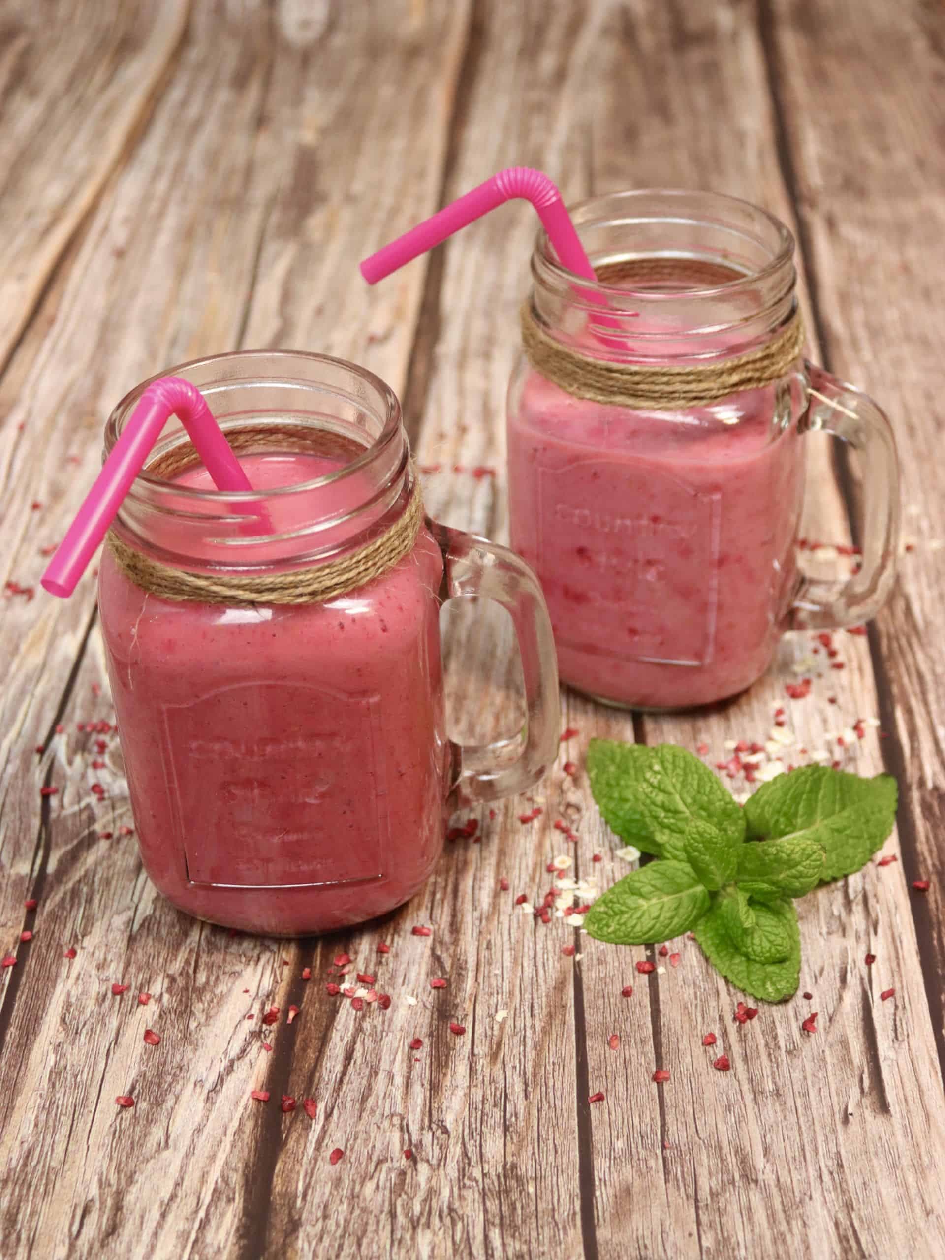 Zwei Beeren-Buttermilch-Drinks auf einem Holztisch