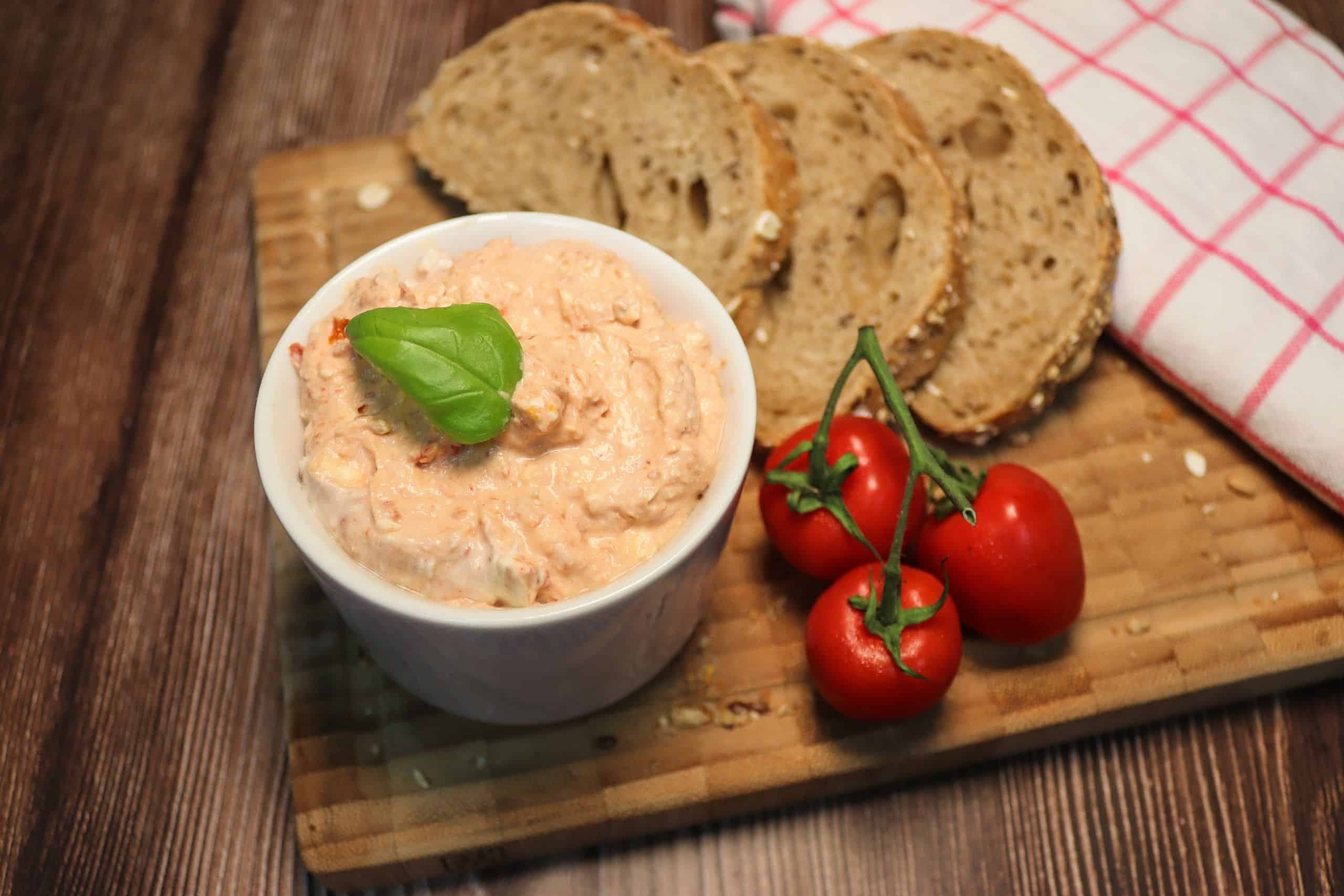 Griechischer Aufstrich mit Körnerbaguette und Tomaten auf einem Brett